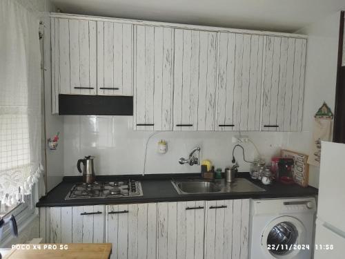 a kitchen with white cabinets and a sink and a stove at CASA GORDON in Navaluenga