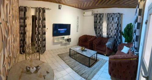 un salon avec deux canapés et une télévision dans l'établissement Trierhouse, à Douala