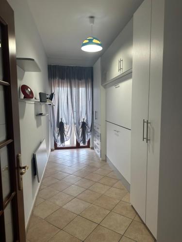 a hallway with white cabinets and a door with curtains at Casa Giovy in Torre del Greco