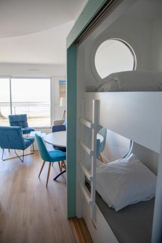 une chambre avec des lits superposés, une table et des chaises dans l'établissement L'océan en toile de fond , appartement cosy, à La Baule