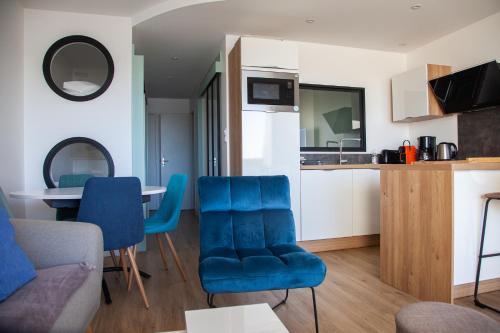 Il comprend un salon avec des chaises bleues et une cuisine. dans l'établissement L'océan en toile de fond , appartement cosy, à La Baule