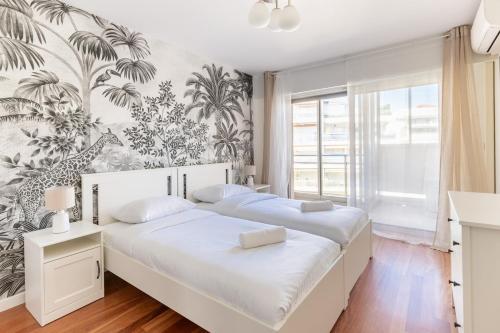 - 2 lits dans une chambre avec papier peint tropical dans l'établissement Luxurious Apartment with Sea and Carlton View, à Cannes