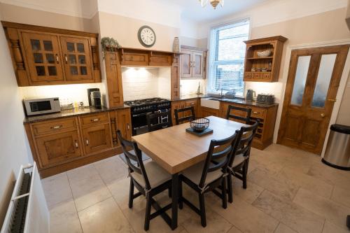 a kitchen with wooden cabinets and a wooden table and chairs at 4 Bed End Terrace - sleeps 7 in Ilkley