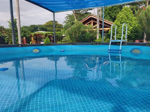 ein blauer Pool mit einem Stuhl im Wasser in der Unterkunft Abenteuer für die ganze Familie - Großzügiges Haus im ZenGarden Paraguay in San Lorenzo de la Frontera