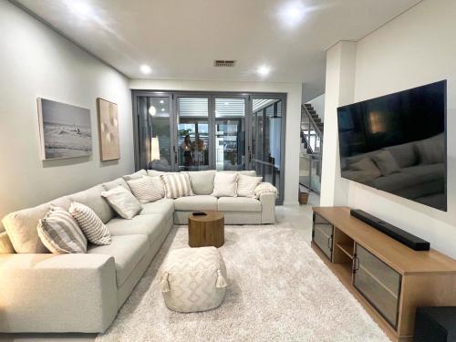 a living room with a white couch and a tv at Cottesloe Beachouse in Perth