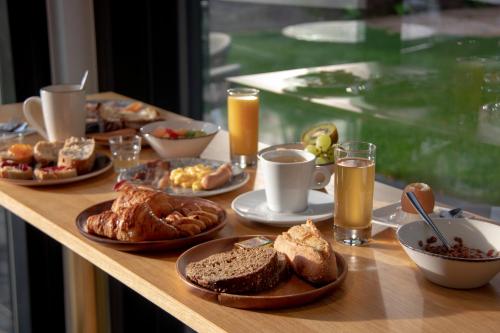 a wooden table with breakfast foods and drinks on it at 6717 Nature Hôtel & Spa Le Clos des Délices in Ottrott