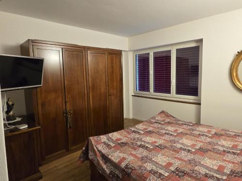 a bedroom with a bed and a cabinet and a television at Il Baitone 1 in Minusio