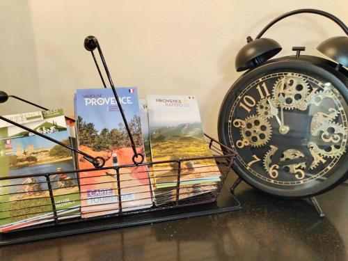 a clock sitting on a shelf with books at Logis Hôtel La Bastide d'Entraigues in Entraigues-sur-la-Sorgue