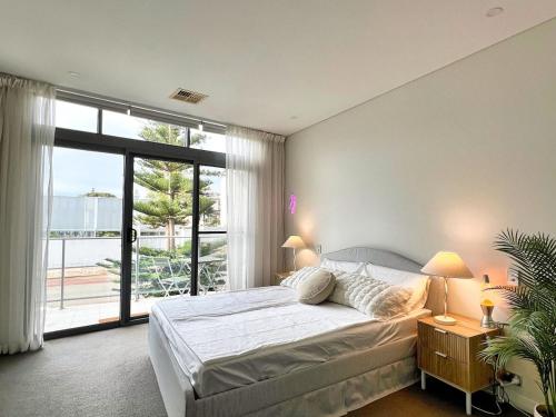 a bedroom with a bed and a large window at Cottesloe Beachouse in Perth