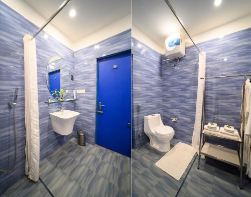 a bathroom with a blue door and a toilet and sink at Sinclairs Retreat Dooars, Chalsa in Chālsa