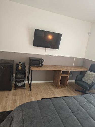 a room with a desk with a tv on a wall at Suítes Lua in Castelo Branco