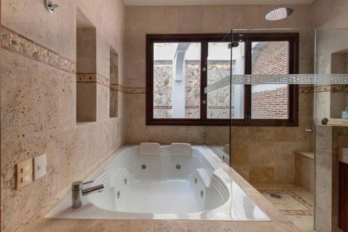 una grande vasca bianca in un bagno con finestra di Luxury Apartment Private Pool & Rooftop Jacuzzi a Cartagena de Indias