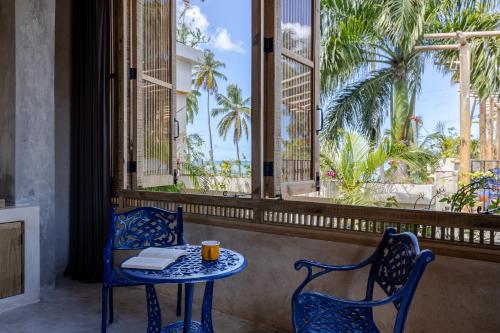 a table and chairs in a room with palm trees at El Mambo Boutique Hotel in Las Terrenas