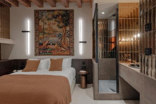 a hotel room with a bed and a tapestry on the wall at MiHotel - Grenier à Sel de Pérouges in Pérouges