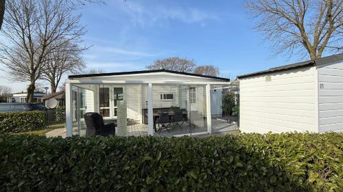 a white house with a conservatory with a table at Chalet am Rhederlaag in Lathum