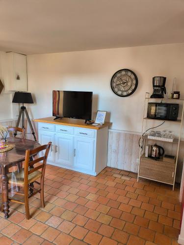 un salon avec une table et une télévision au mur dans l'établissement Maison de campagne, Gîte rouge, à Brigné