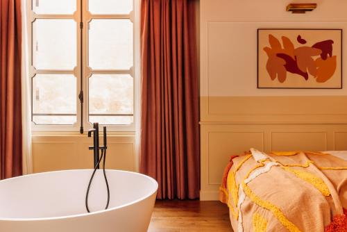 a bathroom with a bath tub next to a bed at Le Jardin de Verre by Locke in Paris