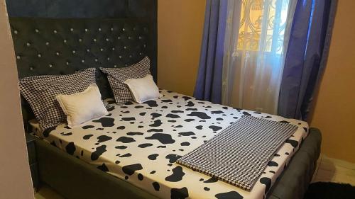 un lit avec une couette et des oreillers noirs et blancs dans l'établissement Trierhouse, à Douala