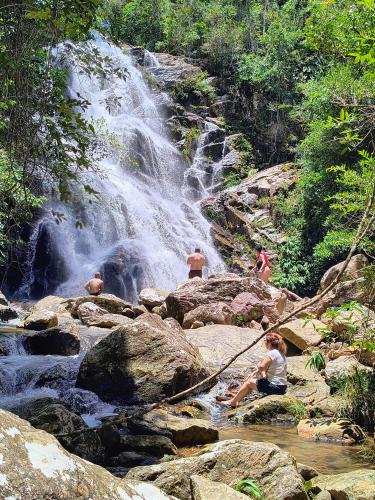 a group of people sitting on rocks near a waterfall at Sons da Canastra Pousada e Terapias - em São José do Barreiro - São Roque de Minas MG in São Roque de Minas
