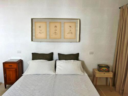 a bedroom with a bed with a picture above it at Villa Li Curti con piscina in comune, un'oasi in paese! in Ortelle