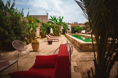 a patio with a red couch and a swimming pool at Villa Li Curti con piscina in comune, un'oasi in paese! in Ortelle
