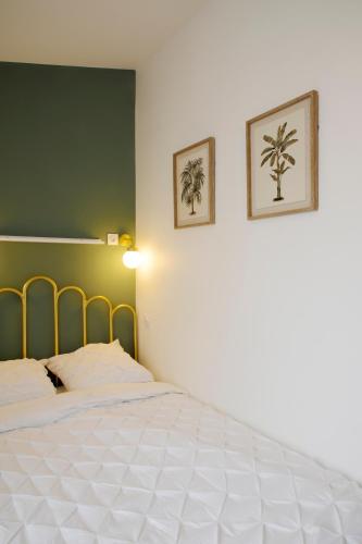 une chambre avec un lit blanc avec deux tableaux au mur dans l'établissement T3 cosy aux portes de Paris, à Saint-Denis