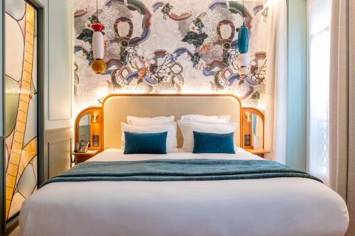 a bedroom with a large bed with blue pillows at Grand Hotel Saint Michel in Paris