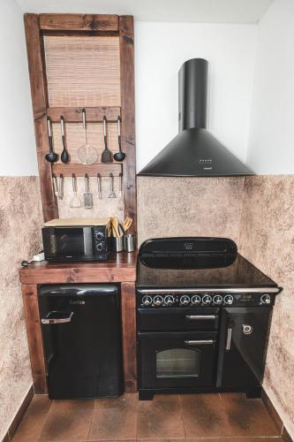 a kitchen with a black stove and a microwave at wellness Chata u Pinkasů in Písečná