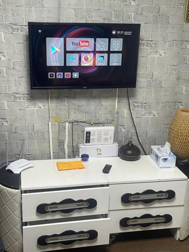 una cassettiera bianca con una TV a parete di Kelly homes a Abu Dhabi
