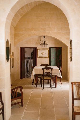 a dining room with a table and chairs at Suites Li Curti, camere con piscina! in Ortelle