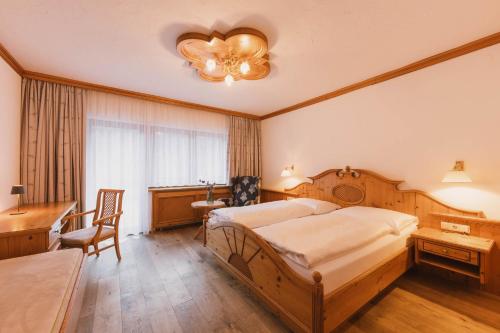 a bedroom with a large bed and a desk and a table at Familotel Kindl in Neustift im Stubaital