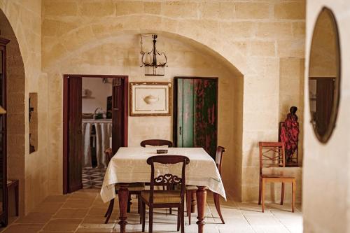 a dining room with a table and chairs at Suites Li Curti, camere con piscina! in Ortelle