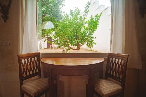 a table and two chairs in front of a window at Suites Li Curti, camere con piscina! in Ortelle