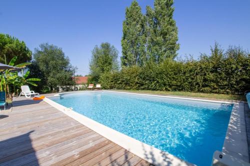 une piscine avec une terrasse en bois à côté d'une maison dans l'établissement Le cedre bleu, à La Chapelle-Aubareil