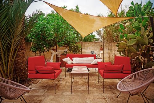 a patio with red chairs and a table at Suites Li Curti, camere con piscina! in Ortelle
