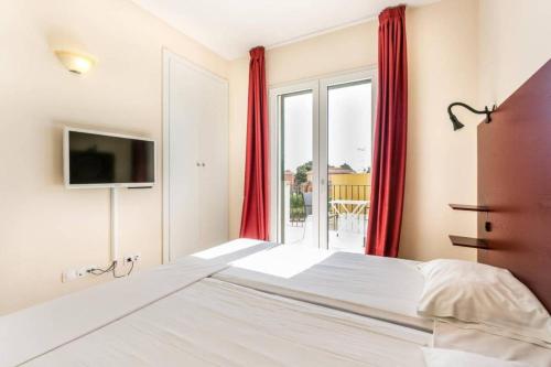 a bedroom with a bed and a window with red curtains at Residence Club el Paraiso 37 in Sa Ràpita