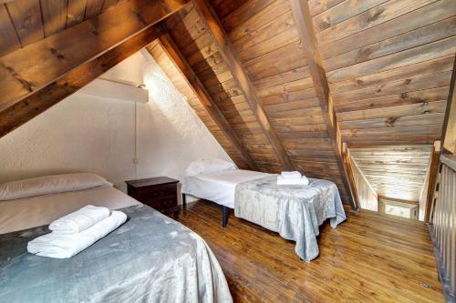a attic room with two beds and a table at Encantadora casa en Salardú con vistas espectaculares by Eth Flòc in Salardú