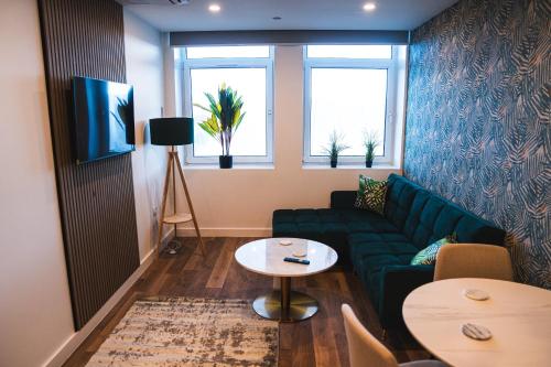 a living room with a green couch and two windows at Royal Apartments Bournemouth in Bournemouth