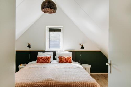a bedroom with a bed with orange and white pillows at Luxe Vakantiehuis Vosje op de Veluwe Nunspeet in Nunspeet