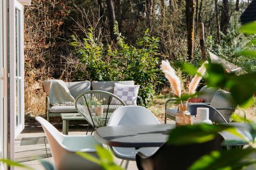 a patio with a table and chairs and a couch at Luxe Vakantiehuis Vosje op de Veluwe Nunspeet in Nunspeet