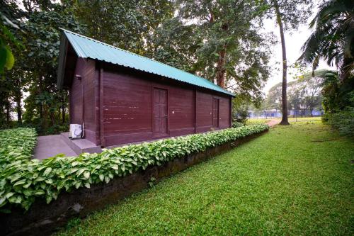 a small wooden building with a blue roof at Sinclairs Retreat Dooars, Chalsa in Chālsa