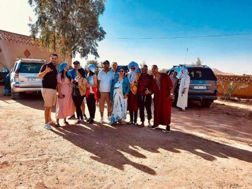 a group of people posing for a picture in the desert at Hotel Les Roches Merzouga in Merzouga