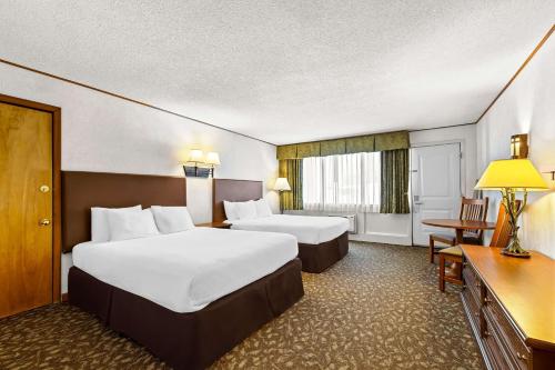 a hotel room with two beds and a desk at Best Western Adirondack Inn in Lake Placid