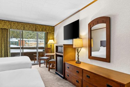 a hotel room with a bed and a mirror at Best Western Adirondack Inn in Lake Placid