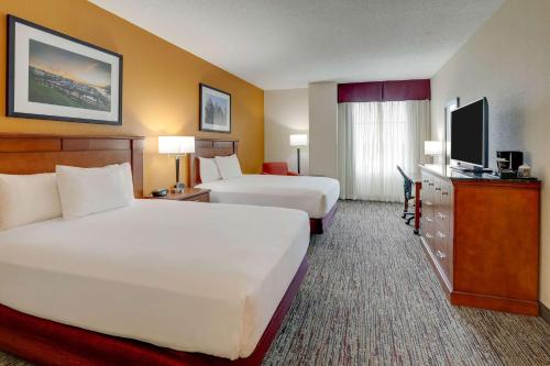 a hotel room with two beds and a flat screen tv at Drury Inn & Suites Charlotte Northlake in Charlotte