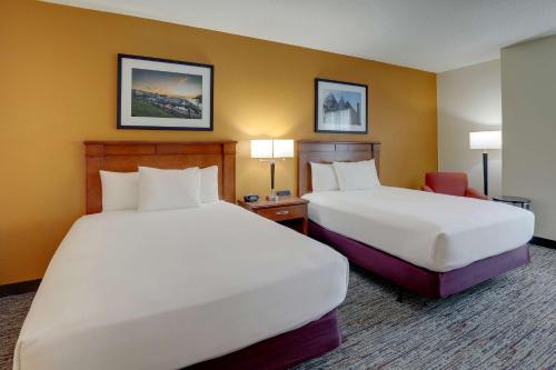 a hotel room with two beds and a chair at Drury Inn & Suites Charlotte Northlake in Charlotte