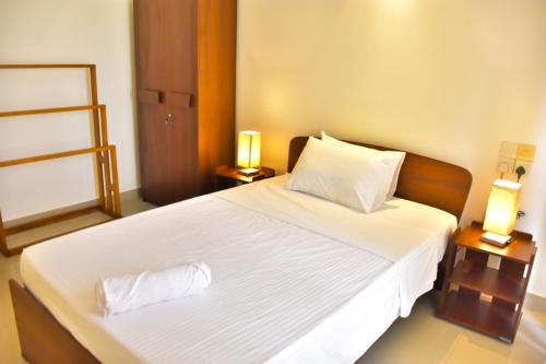 a bedroom with a large white bed with two lamps at Lotus Luxe Residences in Kirillapone