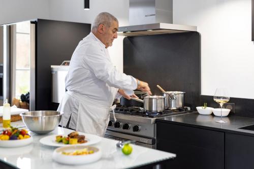 a man in a kitchen preparing food on a stove at La Bastide de Damien, 5 clefs Demeure d'Exception et Table Remarquable dans le guide Teritoria, JACUZZI Privatif, Cuisine étoilée Dominique Frérard in Aix-en-Provence