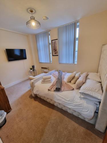 a large white bed in a room with windows at Modern 2BR Flat in Bradford City Centre! in Bradford