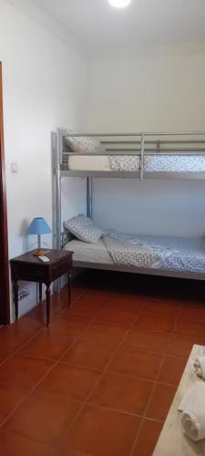 a room with two bunk beds and a table at Caminho da Vila moradia. in Escalos de Cima